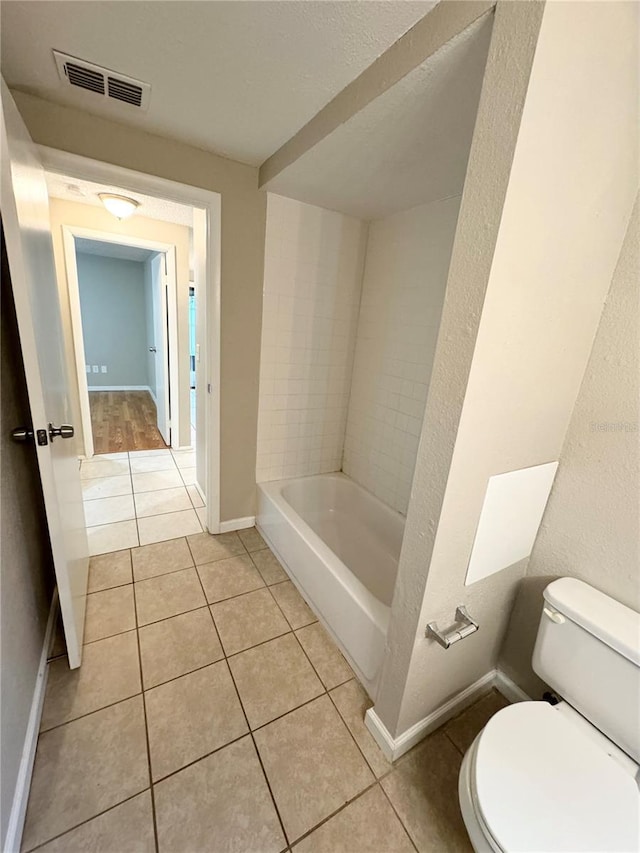 bathroom featuring tile patterned flooring, visible vents, baseboards, a washtub, and toilet