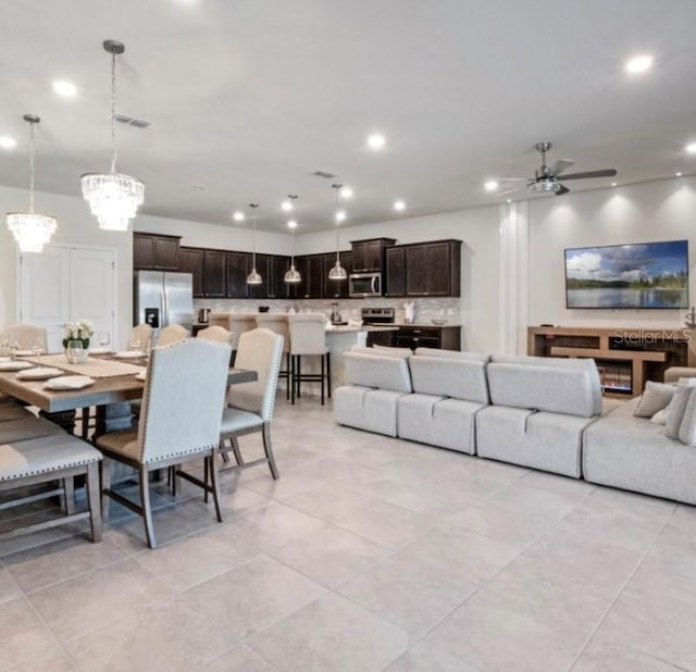 tiled living room featuring ceiling fan with notable chandelier