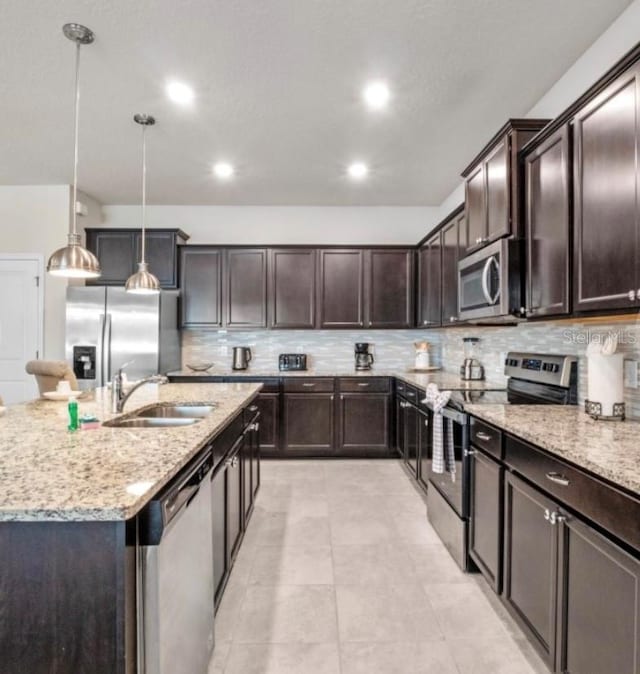 kitchen featuring decorative light fixtures, tasteful backsplash, stainless steel appliances, sink, and light stone counters