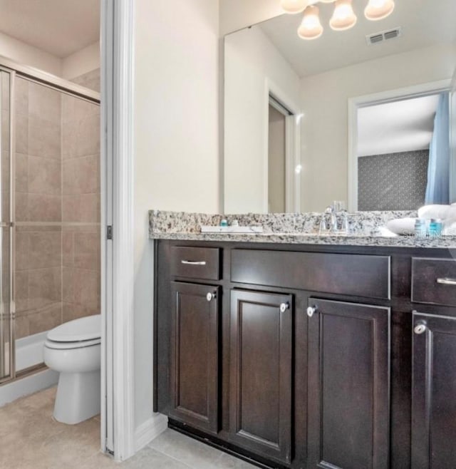 bathroom featuring tile patterned flooring, toilet, a shower with door, and vanity