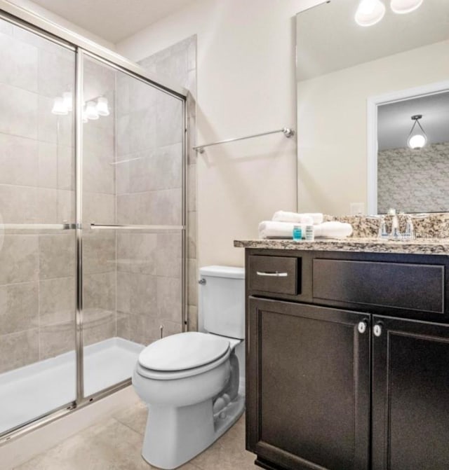 bathroom featuring vanity, toilet, an enclosed shower, and tile patterned floors