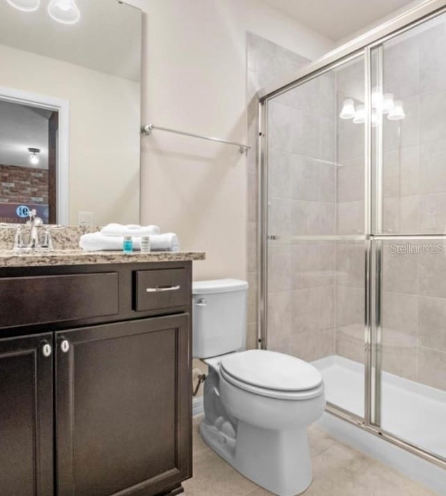 bathroom featuring tile patterned floors, toilet, a shower with door, and vanity