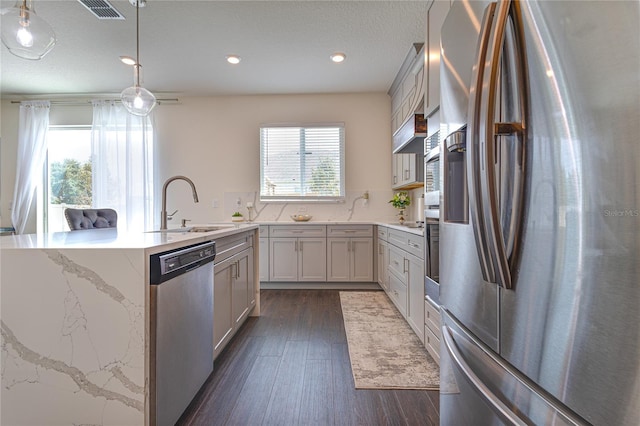 14007 Creek Harbor Dr, Orlando, FL 32824 - kitchen featuring a center island with sink, a sink, appliances with stainless steel finishes, dark wood-style flooring, and hanging light fixtures