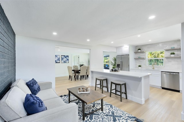 living room with light wood-type flooring, a fireplace, and sink