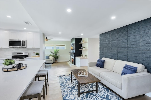 living room with light wood-type flooring and ceiling fan