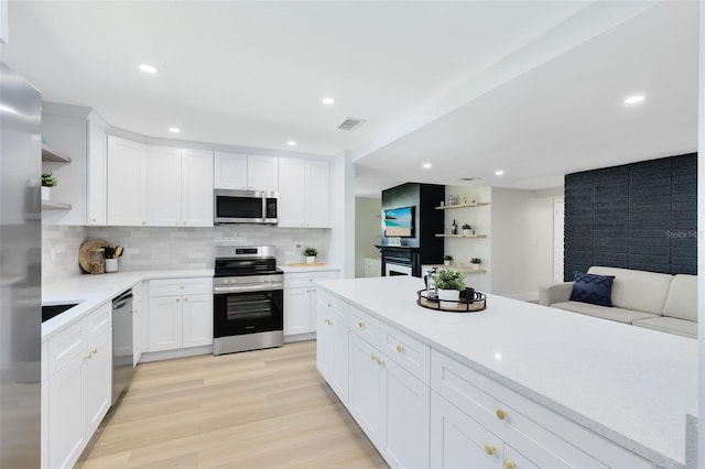 kitchen featuring light hardwood / wood-style flooring, stainless steel appliances, backsplash, and white cabinets