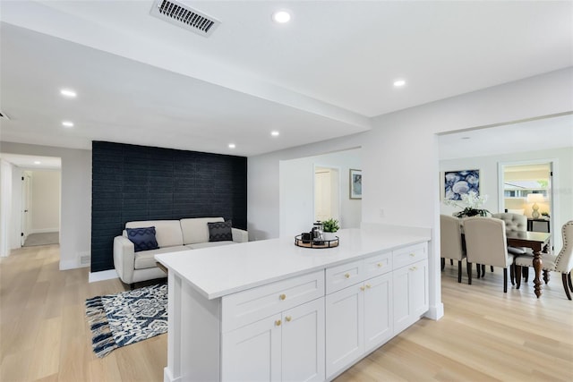 kitchen with light hardwood / wood-style flooring, kitchen peninsula, and white cabinets