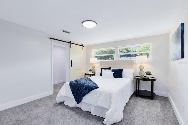 bedroom featuring a barn door and light colored carpet