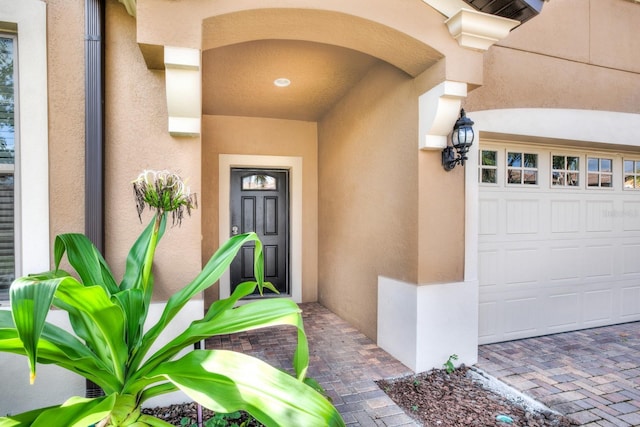 doorway to property with stucco siding and an attached garage