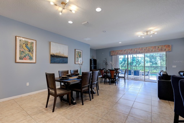 dining room with an inviting chandelier, a textured ceiling, and light tile patterned floors