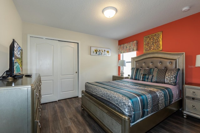 bedroom with a textured ceiling, a closet, and dark hardwood / wood-style flooring