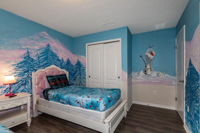 bedroom with a textured ceiling, dark wood-type flooring, and a closet