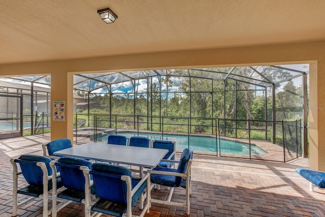 view of patio / terrace featuring glass enclosure and a pool with connected hot tub