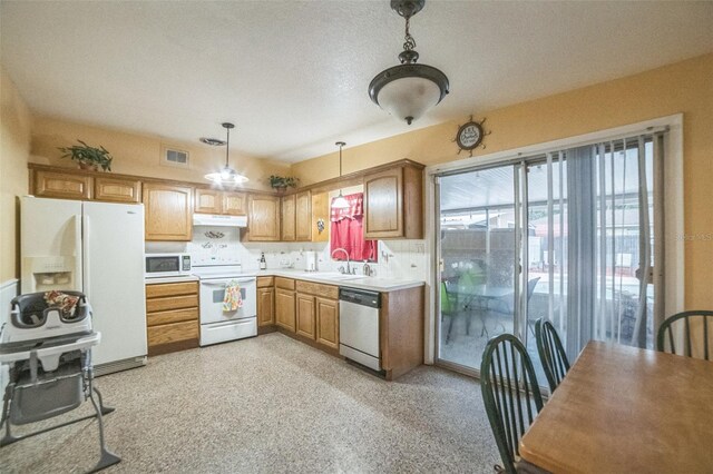 kitchen featuring pendant lighting, white appliances, tasteful backsplash, a textured ceiling, and sink