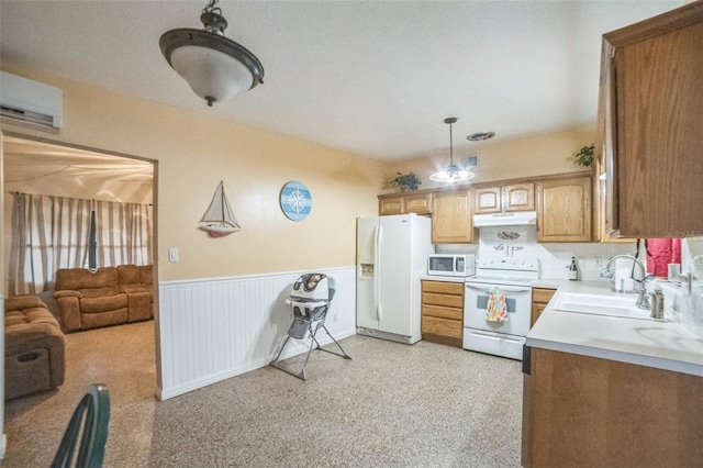 kitchen with a textured ceiling, a wall mounted AC, white appliances, hanging light fixtures, and sink