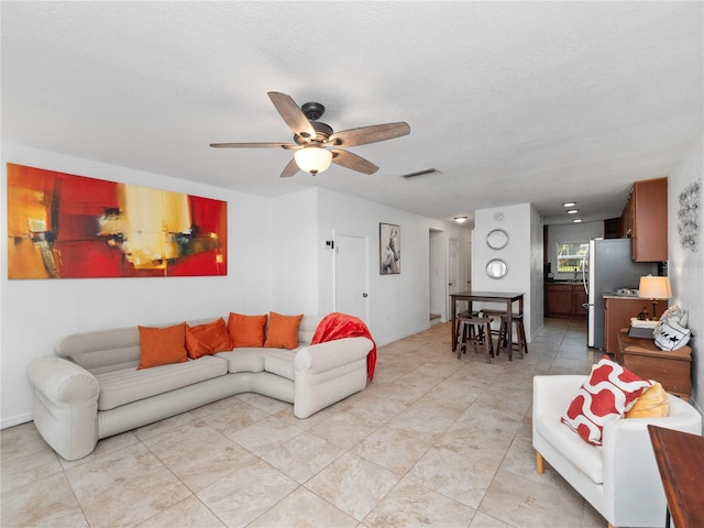 living room featuring a textured ceiling and ceiling fan