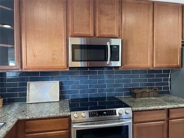 kitchen with light stone counters, stainless steel appliances, and tasteful backsplash