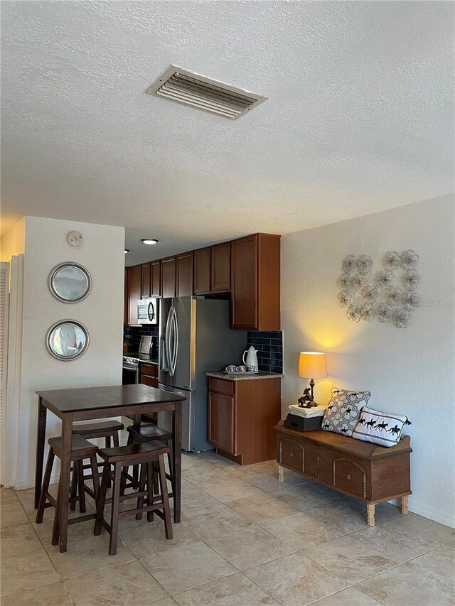 kitchen featuring a textured ceiling, stainless steel appliances, and backsplash