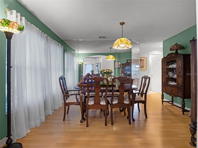 dining space featuring a textured ceiling and light wood-type flooring