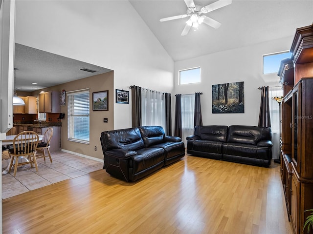 living room with high vaulted ceiling, light wood-type flooring, a textured ceiling, ceiling fan, and sink