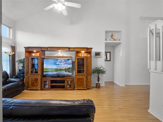 living room with light hardwood / wood-style floors, ceiling fan, and high vaulted ceiling