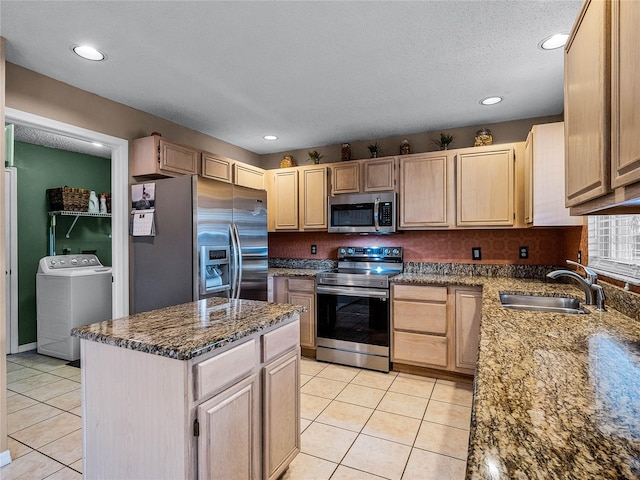 kitchen featuring washer / clothes dryer, sink, stone counters, appliances with stainless steel finishes, and light brown cabinetry