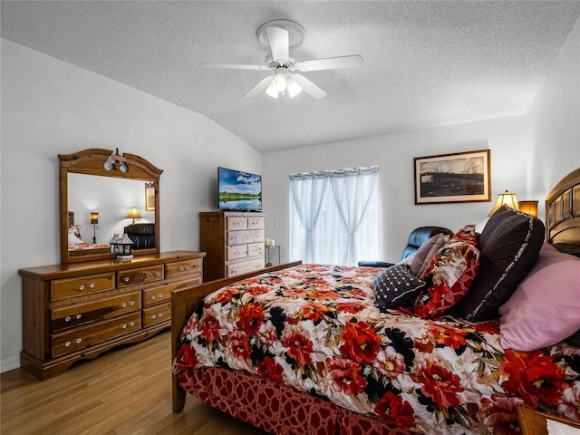 bedroom featuring a textured ceiling, light hardwood / wood-style floors, vaulted ceiling, and ceiling fan