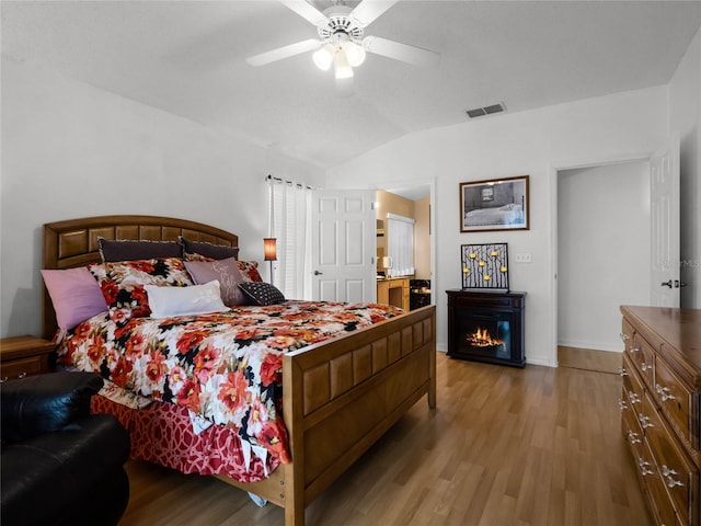 bedroom featuring ceiling fan, light hardwood / wood-style flooring, and lofted ceiling