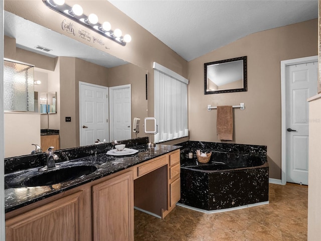 bathroom with vanity, a textured ceiling, vaulted ceiling, and a washtub