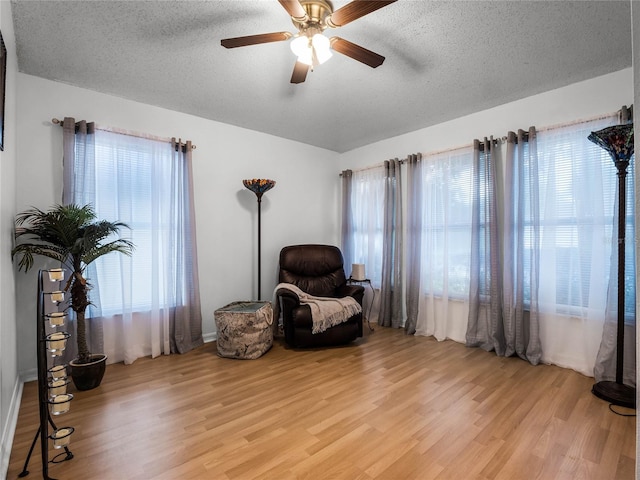 living area featuring light hardwood / wood-style floors, ceiling fan, and a wealth of natural light