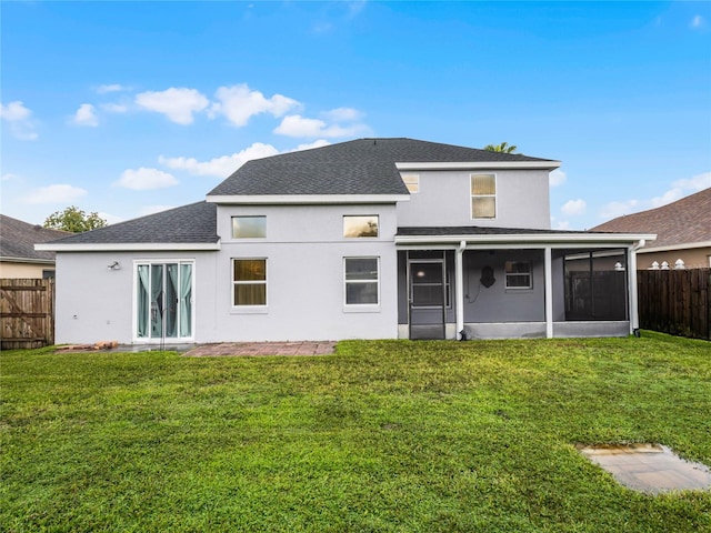 rear view of property with a sunroom and a lawn