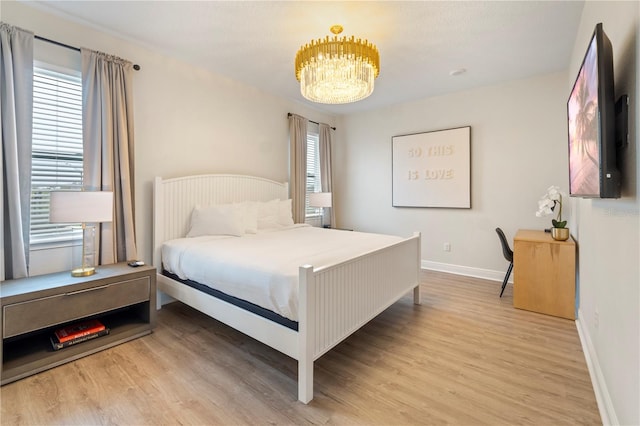 bedroom with light hardwood / wood-style flooring and a chandelier