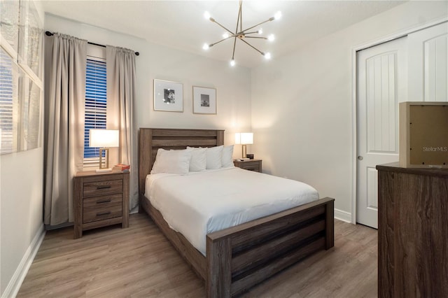 bedroom featuring an inviting chandelier, light wood-type flooring, and a closet