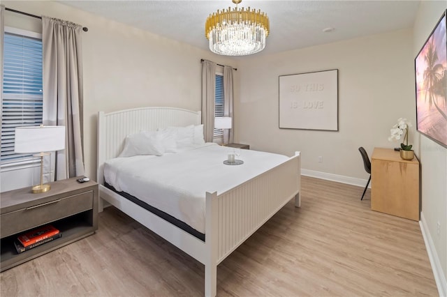 bedroom with an inviting chandelier and light hardwood / wood-style floors