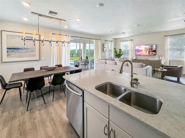 kitchen with light stone counters, pendant lighting, light wood-type flooring, an inviting chandelier, and sink