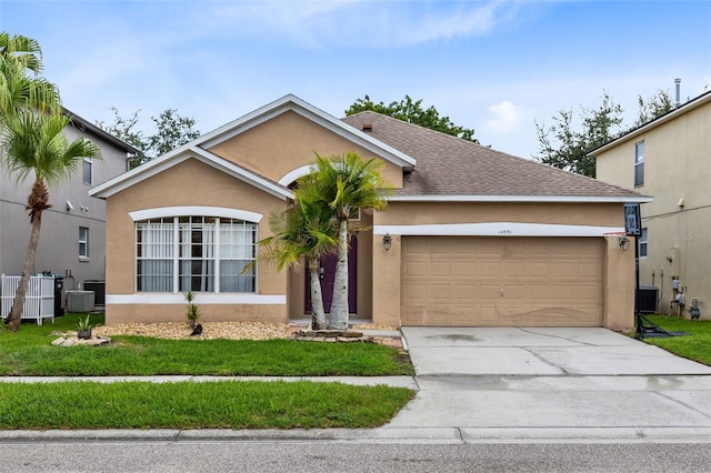 view of front of property featuring a garage, a front lawn, and central air condition unit