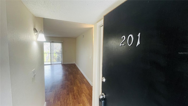 corridor with hardwood / wood-style flooring and a textured ceiling