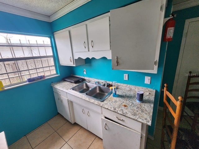 kitchen featuring white cabinets, light tile patterned floors, a textured ceiling, sink, and ornamental molding