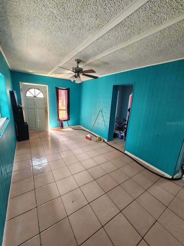 entryway with a textured ceiling, ceiling fan, ornamental molding, and light tile patterned floors