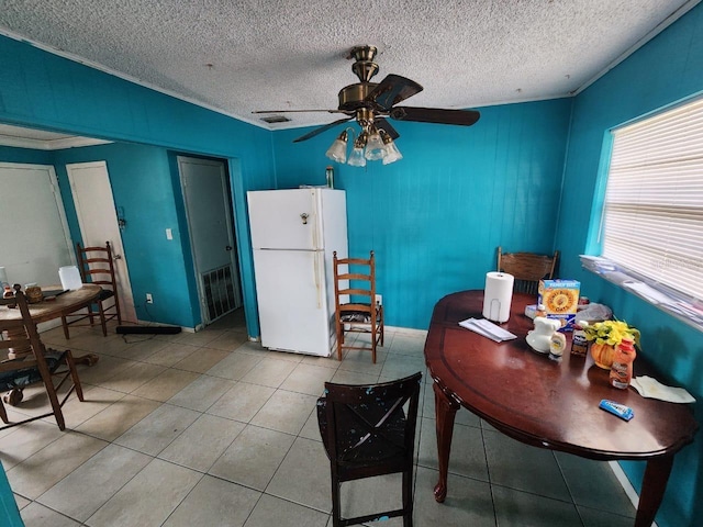 interior space with a textured ceiling, light tile patterned floors, and ceiling fan