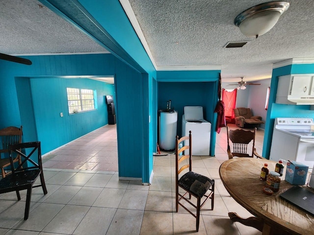 living room featuring washer / dryer, a textured ceiling, ceiling fan, and wooden walls