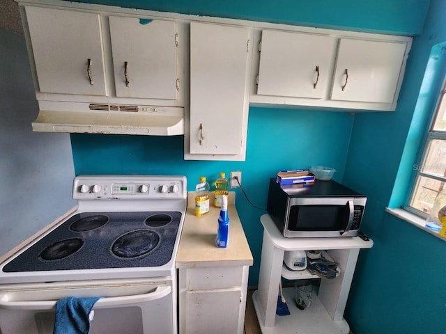 kitchen with white electric stove and white cabinetry