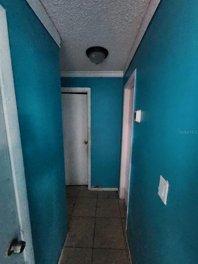 corridor with a textured ceiling and tile patterned flooring