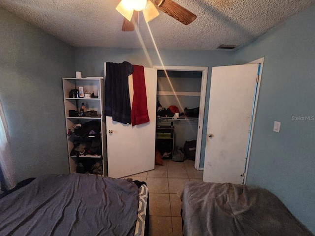 bedroom with a closet, ceiling fan, a textured ceiling, and tile patterned flooring