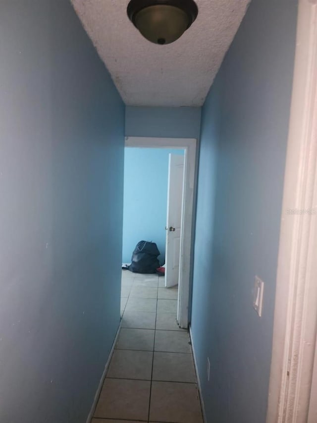 hall featuring light tile patterned floors and a textured ceiling