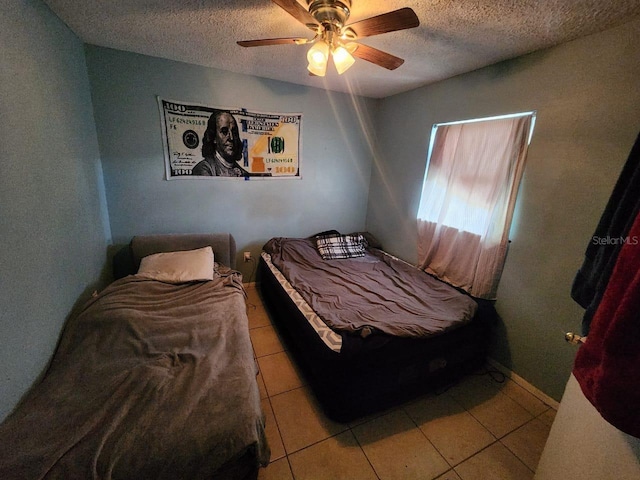 bedroom with ceiling fan, light tile patterned floors, and a textured ceiling