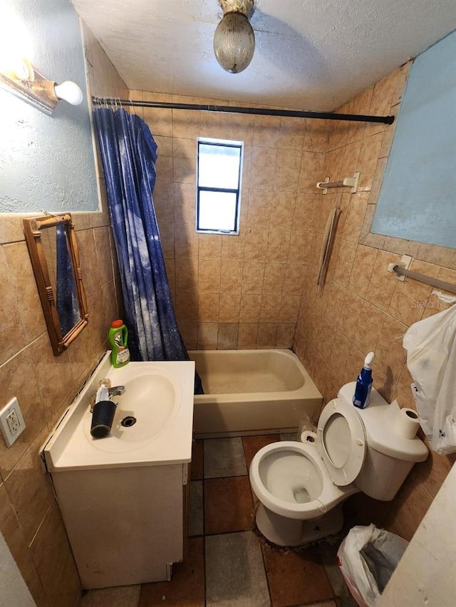 full bathroom featuring a textured ceiling, vanity, tile walls, toilet, and shower / bath combo