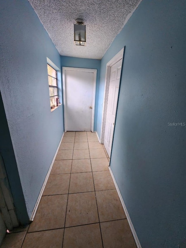 hall featuring a textured ceiling and light tile patterned floors