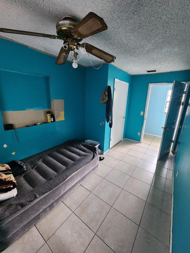 unfurnished bedroom with a textured ceiling, ceiling fan, and tile patterned flooring