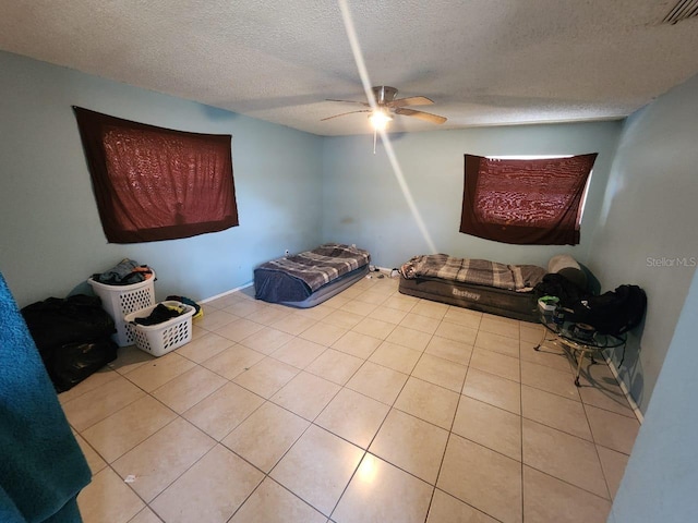 interior space featuring a textured ceiling, light tile patterned flooring, and ceiling fan